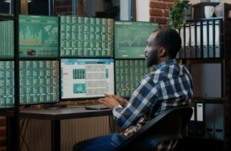 man sitting infront of computer showing trading charts