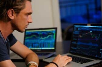 man looking at trading chart on two laptops