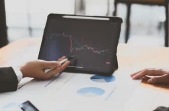 person pointing to tablet showing forex chart that is red and green